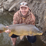 Chris Galvin holds 21 pound common carp with surprised smile.