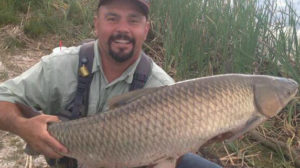 Mike Medina holding a 30 pound Colorado grass carp with a big smile.