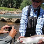 One man taking a picture of another man who is holding a trophy sized trout along the banks of the North Fork of the South Platte, near Bailey.