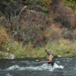 Competitive angler Chris Galvin fighting a fish in heavy river current