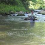 Chris Galvin running through river with trout in net