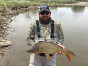 A happy fly fisherman with a big carp he caught in a Denver lake.